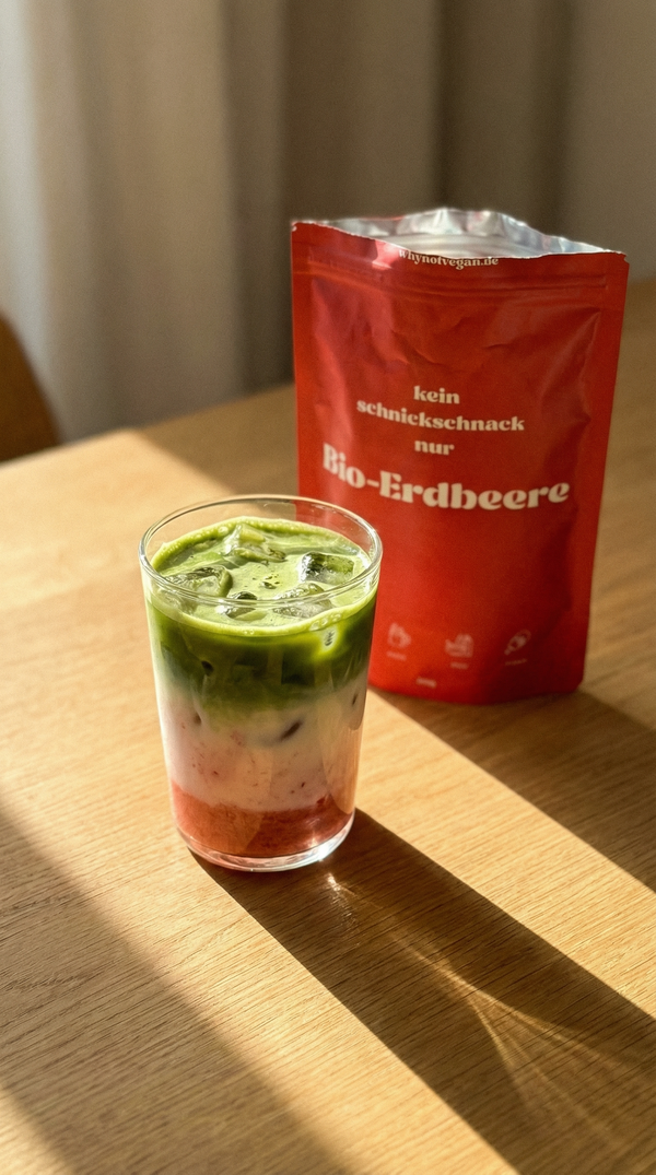 Layered Matcha Drink mit Erdbeer-Basis, Milch und Eis im Glas, Bio Erdbeerpulver von whynotvegan im Hintergrund